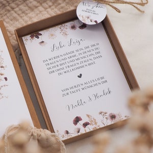 May include: A white card with a floral design and the text "Liebe Luiza. Da werden H&auml;nde sein, die dich tragen und Arme, in denen du sicher bist und Menschen, die dir ohne fragen zeigen, dass du willkommen bist. Von Herzen alles Liebe zur Taufe w&uuml;nschen dir Malita & Hendrik"