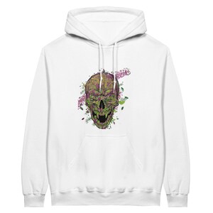 May include: White hooded sweatshirt featuring a detailed graphic of a green and purple skull with an open mouth. The skull design is surrounded by floral accents. The sweatshirt has a front pocket and a drawstring hood.