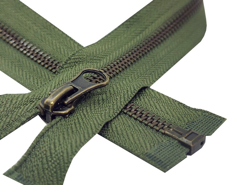 K&ouml;nnte beinhalten: Nahaufnahme eines gr&uuml;nen Rei&szlig;verschlusses mit einem Messing-Schieber und -Zipper. Der Rei&szlig;verschluss ist ge&ouml;ffnet und die Z&auml;hne sind sichtbar.