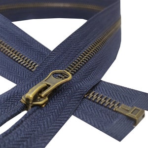 K&ouml;nnte beinhalten: Nahaufnahme eines marineblauen Rei&szlig;verschlusses mit einem Messing-Schieber und -Zipper. Der Rei&szlig;verschluss ist ge&ouml;ffnet und die Z&auml;hne sind sichtbar.