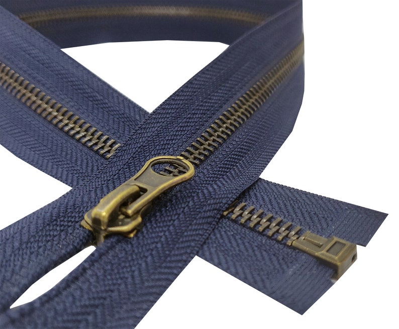 K&ouml;nnte beinhalten: Nahaufnahme eines marineblauen Rei&szlig;verschlusses mit einem Messing-Schieber und -Zipper. Der Rei&szlig;verschluss ist ge&ouml;ffnet und die Z&auml;hne sind sichtbar.