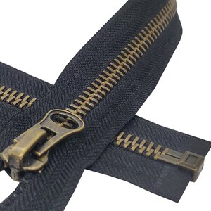 K&ouml;nnte beinhalten: Ein schwarzer Rei&szlig;verschluss mit einem Messing-Schieber und -Zipper. Der Rei&szlig;verschluss ist geschlossen und die Z&auml;hne sind sichtbar.