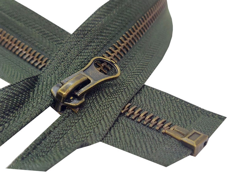K&ouml;nnte beinhalten: Nahaufnahme eines gr&uuml;nen Rei&szlig;verschlusses mit einem Messing-Schieber und -Zipper. Der Rei&szlig;verschluss ist ge&ouml;ffnet und die Z&auml;hne sind sichtbar.