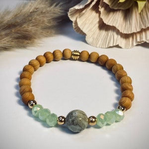 Könnte beinhalten: Ein Armband aus Holzperlen mit einem grünen Steinperle und goldenen Akzenten. Das Armband ist aus natürlichen Holzperlen gefertigt und hat ein schlichtes, elegantes Design.