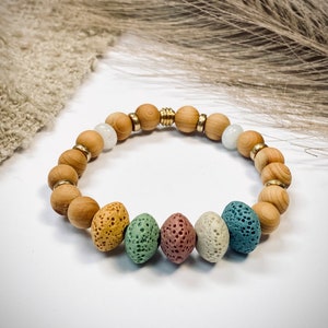 Könnte beinhalten: Ein Armband aus Holzperlen und bunten Lavasteinen. Das Armband hat einen goldenen Akzent.