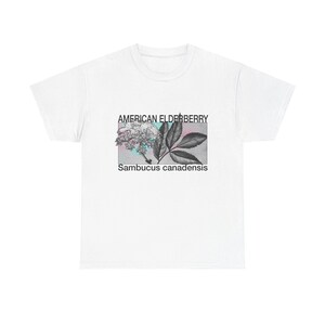 以下が含まれることがあります： アメリカニワトコ植物の植物図が描かれた白いTシャツ。デザインには、植物の花と葉の詳細な図と、その上下に「AMERICAN ELDERBERRY」と「Sambucus canadensis」の文字が印刷されています。