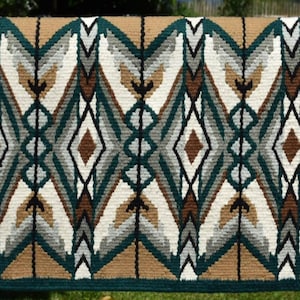 Könnte beinhalten: Eine gewebte Satteldecke in Grün, Braun, Weiß und Grau mit einem geometrischen Rautenmuster.