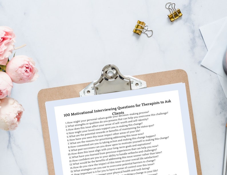 May include: A brown clipboard with a white sheet of paper on it. The paper has the title "100 Motivational Interviewing Questions for Therapists to Ask Clients". The questions are listed in a numbered format.