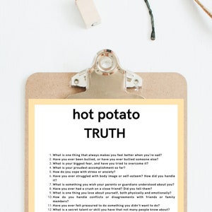 Puede incluir: Un portapapeles con respaldo de madera marr&oacute;n claro y clip met&aacute;lico plateado sostiene un papel amarillo con las palabras "hot potato TRUTH" y una lista de preguntas. El fondo es blanco con algunos objetos peque&ntilde;os.