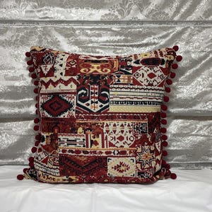 Burgundy cushion on a grey sofa against a silver backdrop, boho patchwork design