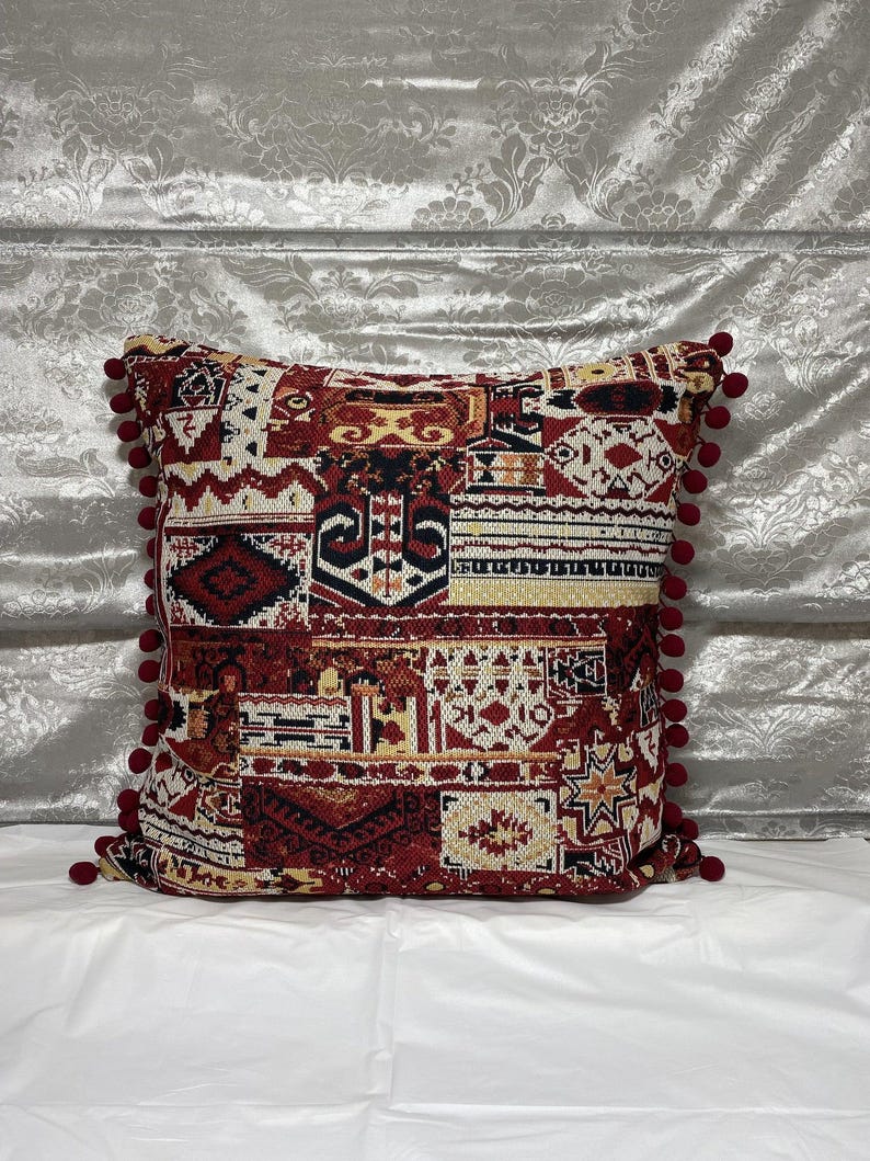 Burgundy cushion on a grey sofa against a silver backdrop, boho patchwork design