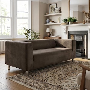 May include: A brown, contemporary sofa with a low profile and square arms. The sofa sits on silver legs and is in a living room with a patterned rug and a fireplace. The sofa's length is approximately 200 cm.