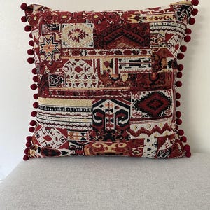 Patchwork cushion in burgundy and cream on a grey sofa, front view
