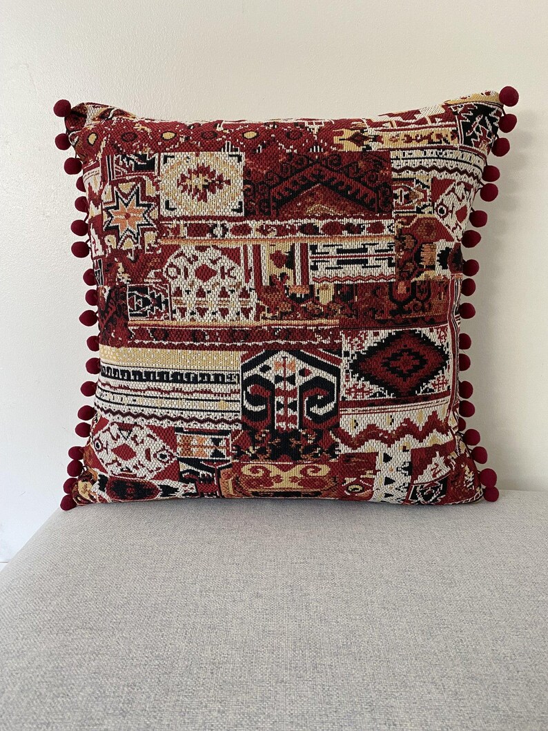 Patchwork cushion in burgundy and cream on a grey sofa, front view