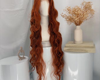 May include: A long, wavy, copper-red wig displayed on a white mannequin head. The hair features a center part and flows down in loose, voluminous curls. The wig is positioned on a white cylindrical stand, showcasing its length and texture.