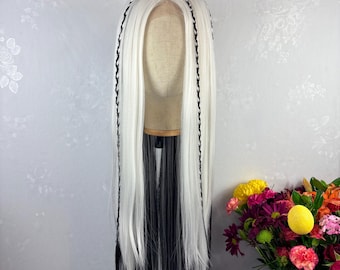 May include: A long, white wig with black streaks at the bottom and black braided accents. The wig is displayed on a mannequin head. The hair is straight and falls to a long length. A bouquet of colorful flowers is in the background.