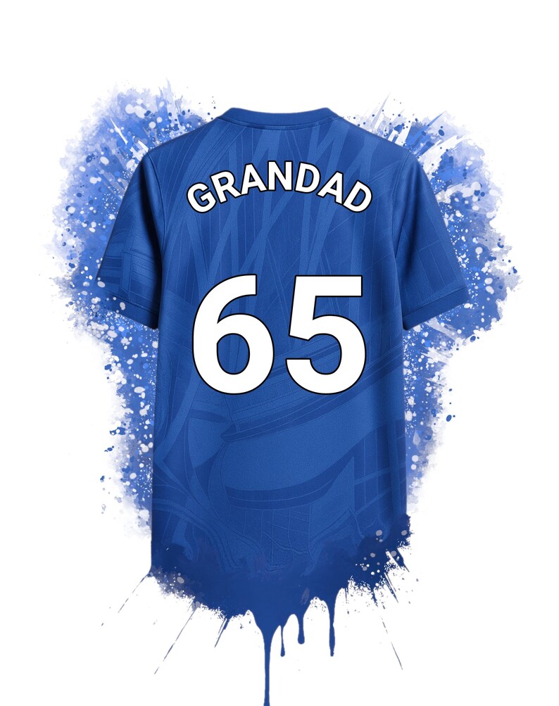 May include: A blue short-sleeved t-shirt featuring the word GRANDAD and the number 65 in white lettering on the back. The shirt has a subtle tonal pattern and is surrounded by a blue paint splatter effect that drips from the bottom hem.