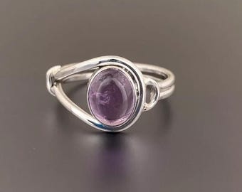 May include: A silver ring with a purple amethyst gemstone set in a delicate, curved band.