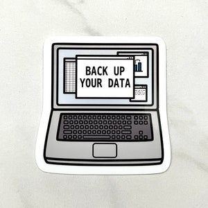 以下が含まれることがあります： 「BACK UP YOUR DATA」の文字が画面に表示された、ノートパソコンのデザインのステッカー。ノートパソコンはグレーと黒で、白い縁取りがあります。画面にはスプレッドシートと棒グラフが表示されています。