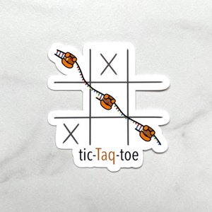 May include: A white sticker featuring a tic-tac-toe board with 'X' marks and a DNA-like strand with orange enzyme-like figures. The text 'tic-Taq-toe' is written in brown below the board.