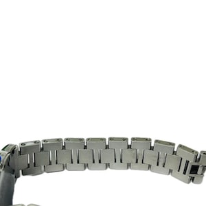 May include: Close-up of a silver-toned watch bracelet. The bracelet is composed of rectangular links, with a clasp visible at the end. The watch has a blue and green accent on the side.