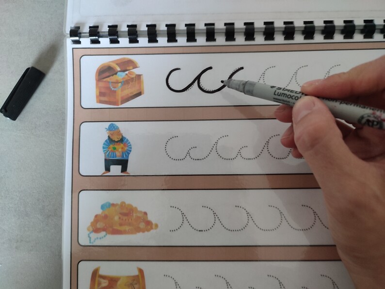 May include: A workbook with dotted lines for tracing the letter "c" and wavy lines. The page features illustrations of a treasure chest, a pirate, and a pile of gold coins.