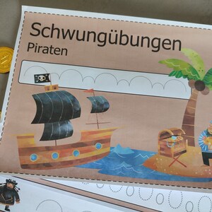 May include: A worksheet with the title "Schwung&uuml;bungen Piraten" featuring a pirate ship, a palm tree, a treasure chest, and a pirate holding a treasure chest. The worksheet has dotted lines for tracing.
