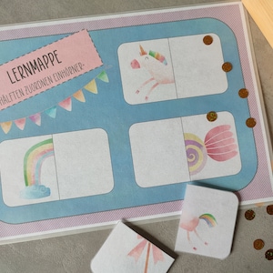 Può includere: Una mappa di apprendimento con il titolo "Lernmappe - Hälften zuordnen Einhörner" con un arcobaleno, un unicorno e un design a spirale. La mappa è divisa in quadrati con metà corrispondenti delle immagini.