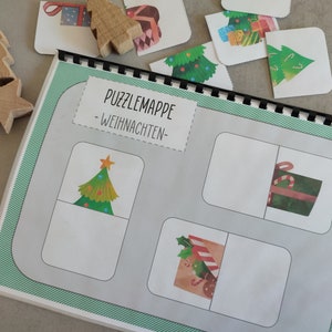 Könnte beinhalten: Eine Weihnachts-Puzzlekarte mit grünem Hintergrund und weißen Puzzle-Teilen. Der Titel der Puzzlekarte lautet "Puzzlemappe - Weihnachten -" und es sind Bilder von einem Weihnachtsbaum und Geschenken zu sehen.