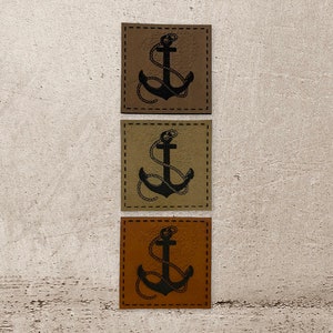 Könnte beinhalten: Drei Leder-Patches mit einem schwarzen Anker-Design. Die Patches sind braun, beige und orange.