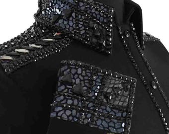 May include: Black equestrian show shirt with embellished collar, shoulder accents, and cuffs. The collar and cuffs feature a mosaic-like pattern with dark blue and black accents. The shirt has a button-down front and the brand name "SARA" is visible.