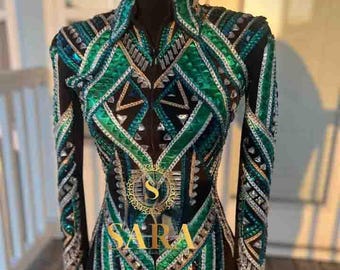 May include: A long-sleeved jacket with a black mesh base, adorned with intricate patterns of green, silver, and gold embellishments. The jacket features a high collar and a zipper closure. The word "SARA" is displayed on the front.
