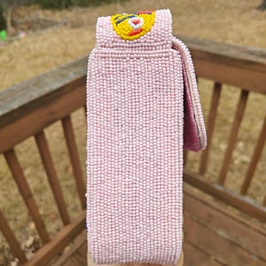 Full side view showing the depth of the sardines beaded bag and the attachment point of the beaded strap. This pink seed bead bag is built with a blend of canvas and suede for durability. The image displays the uniform bead patterns that cover every inch of the novelty beaded purse. As a handmade Indian beaded bag, it offers a sophisticated yet playful silhouette, making it an excellent choice for a summer beach outing or a unique gift for her.