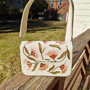 Peach floral ivory beaded shoulder bag handmade with seed bead embroidery on ivory fabric, artisan evening handbag featuring peach flower and gold leaf beadwork design with structured top handle, elegant beaded purse for wedding guest, bridal shower, spring party or formal event, luxury handcrafted floral handbag, cottagecore statement purse, unique handmade beaded bag gift for her, romantic evening clutch style shoulder bag, artisan embroidered fashion accessory.