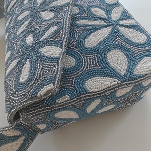 This side profile shot highlights the depth and structural integrity of the Chinoiserie style accessory, focusing on the reinforced gusset. The floral beaded bag maintains its shape even when empty, showcasing the professional tension of the hand-sewn beads. In terms of scale, the side view reveals a two-inch thickness, confirming it is a substantial party evening floral piece that offers more internal volume than a traditional flat envelope clutch.