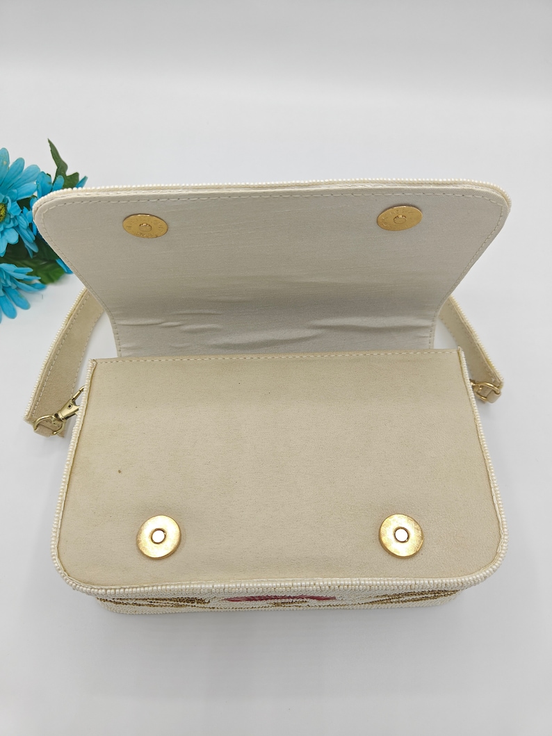 Beaded handbag interior view with ivory fabric lining and magnetic snap closure, handmade artisan purse inside compartment showing clean spacious design, structured evening bag interior with soft textile lining and secure flap closure, elegant handcrafted beaded shoulder bag inside detail, bridal or wedding guest handbag storage space for phone, makeup and essentials, luxury handmade purse interior construction.