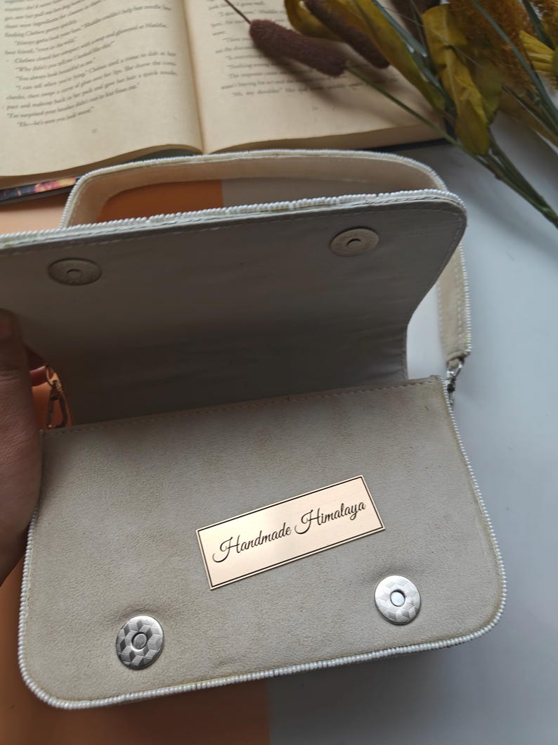 Handmade beaded handbag interior view with soft ivory fabric lining and magnetic snap closure, artisan evening purse inside compartment showing spacious storage for phone, wallet and makeup essentials, elegant handcrafted beaded shoulder bag interior with structured design and secure flap closure, luxury bridal or wedding guest handbag inside detail, designer handmade purse construction, artisan evening clutch interior.