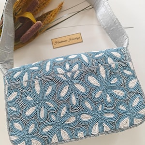 The back view of this Grandmillennial Bag demonstrates the continuous, uninterrupted seed bead wedding craftsmanship that wraps around the entire piece. The silver-grey beaded strap is shown attached at the sides, reinforcing its durability as a luxury beaded bag. To assist with visual search intent, the scale of the back panel is identical to the front, providing a sleek, snag-free surface that rests comfortably against a silk or lace dress.