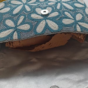 This interior view reveals the magnetic snap closure and the smooth satin lining of the Dusty Blue Wedding accessory, showcasing the high-quality finish. The underside of the flap continues the embroidered flower bag motif, ensuring beauty from every angle. For scale, the open compartment is shown to be deep enough to securely fit a smartphone (Iphone Pro max models), a slim wallet, and daily essentials, proving its utility as a functional Spring Formal Bag.