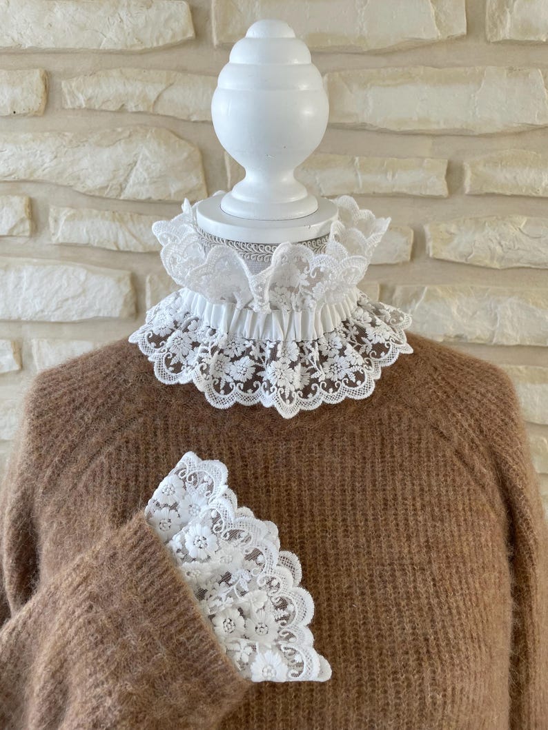 May include: A brown sweater with a white lace collar and matching lace cuffs.