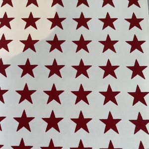 May include: A sheet of white paper with a repeating pattern of 48 red stars.