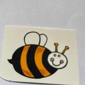 Pode incluir: Uma abelha de desenho animado amarela e preta com uma asa branca e um rosto sorridente. A abelha tem um corpo listrado de preto e amarelo.