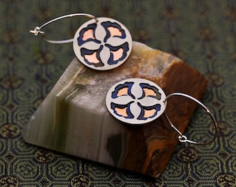 Round hoop earrings featuring a four-ginkgo-leaf motif in warm copper and sleek silver.