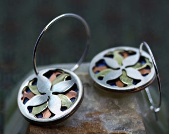 Round hoop earrings, adorned with a refined abstract floral motif in blue, orange, and silver.