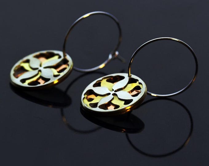 Round hoop earrings, adorned with a refined abstract floral motif in blue, orange, and silver.