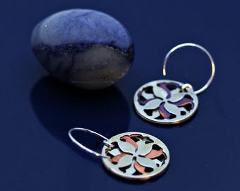 Orange and silver round hoop earrings adorned with a refined abstract floral motif.