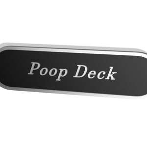 Könnte beinhalten: Ein silbernes und schwarzes Metallschild mit dem Text "Poop Deck" in weißen Buchstaben.