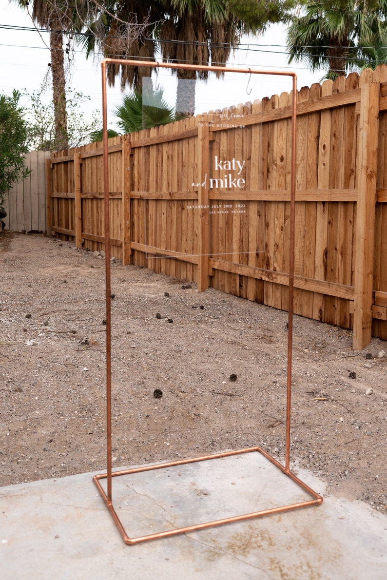 Full length copper sign stand displaying an acrylic wedding welcome sign.