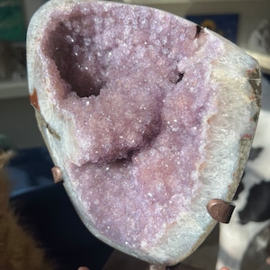 May include: A large amethyst geode with a purple and white crystal interior. The geode is mounted on a metal stand.