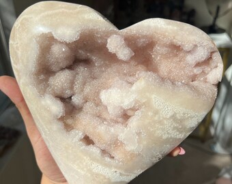 May include: A heart-shaped geode with a white exterior and a pink and white crystal interior.